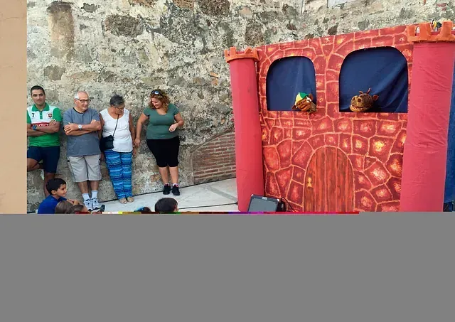 Un grupo de personas está de pie frente a un teatro de marionetas.