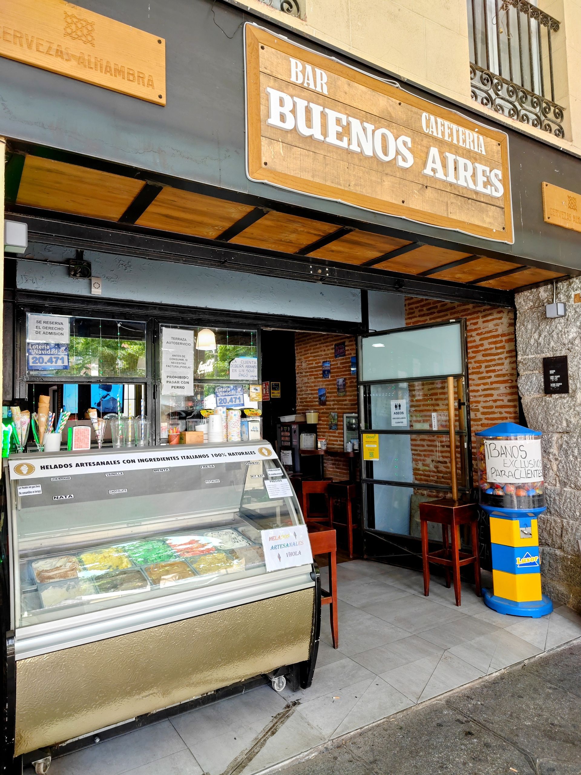 Exterior del Bar Buenos Aires, cafetería con vitrina y cartel de madera.
