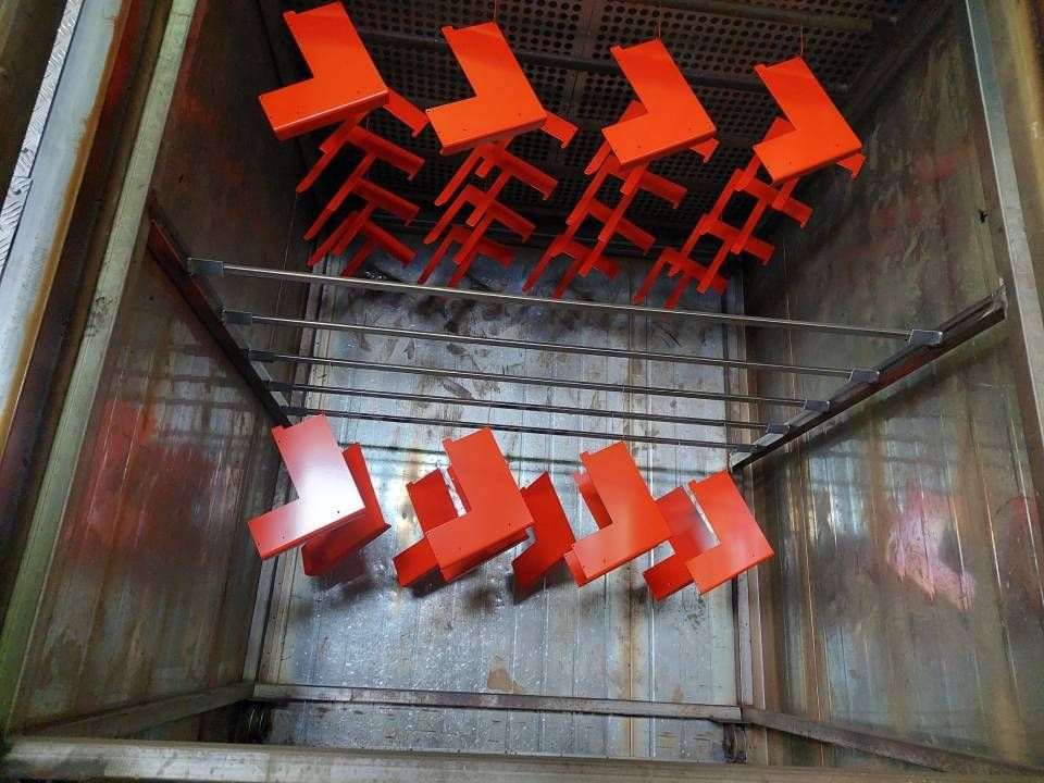Orangefarbene Metallwinkel hängen in einem Industrieofen.