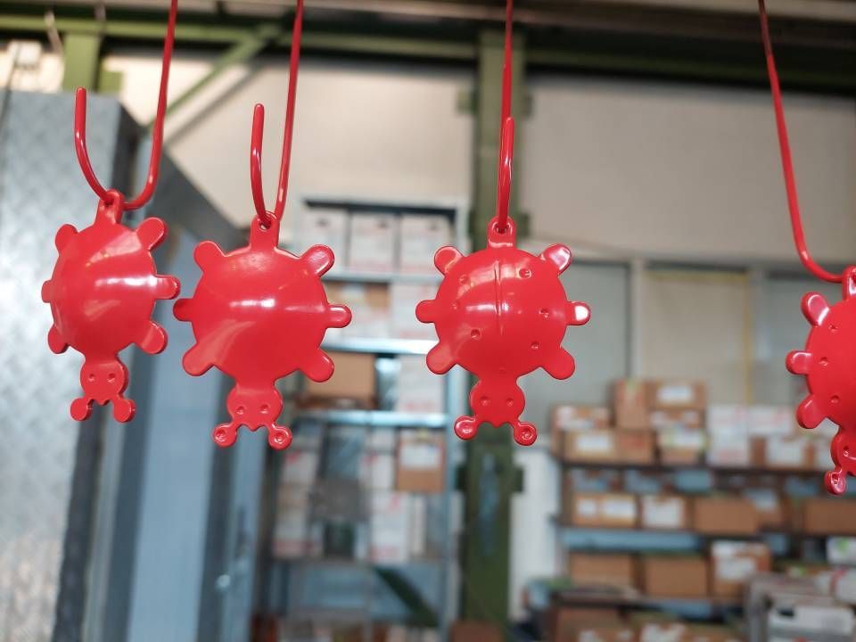 Rote Metallgegenstände hängen in einer Werkstatt, möglicherweise frisch lackiert.