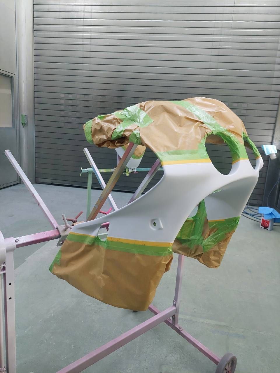 Motorradverkleidung, teilweise mit Klebeband abgeklebt, in einer Lackierkabine.