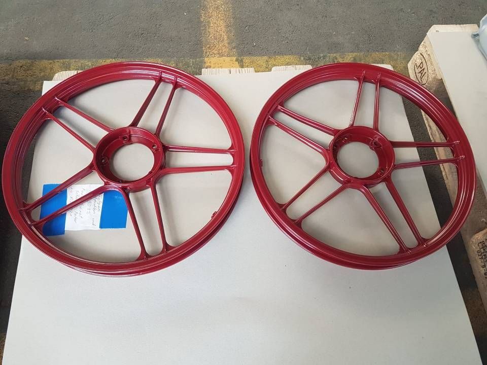 Zwei rote Motorradräder nebeneinander auf hellgrauem Untergrund.