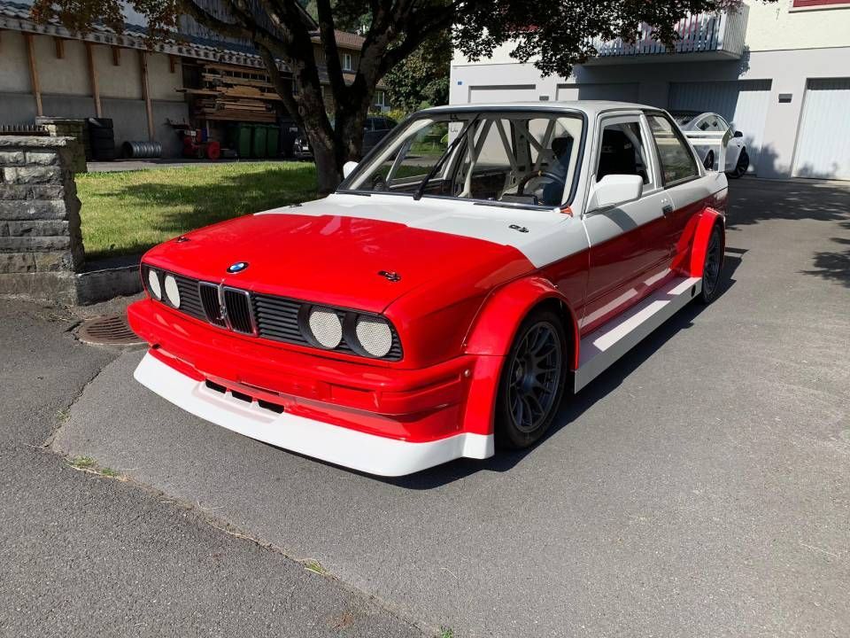 Ein rot-weisser BMW-Sportwagen mit breiten Kotflügeln steht auf Asphalt.