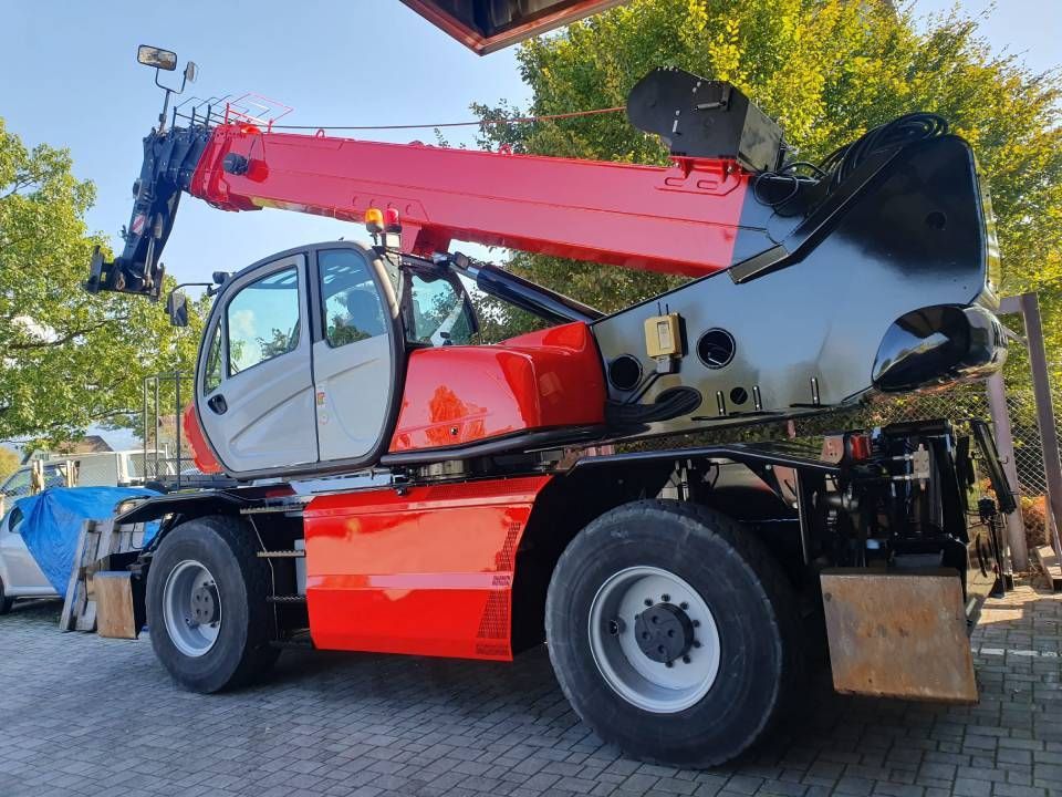 Roter und schwarzer Teleskoplader auf Rädern, im Freien. Ausleger ausgefahren, Kabine sichtbar.