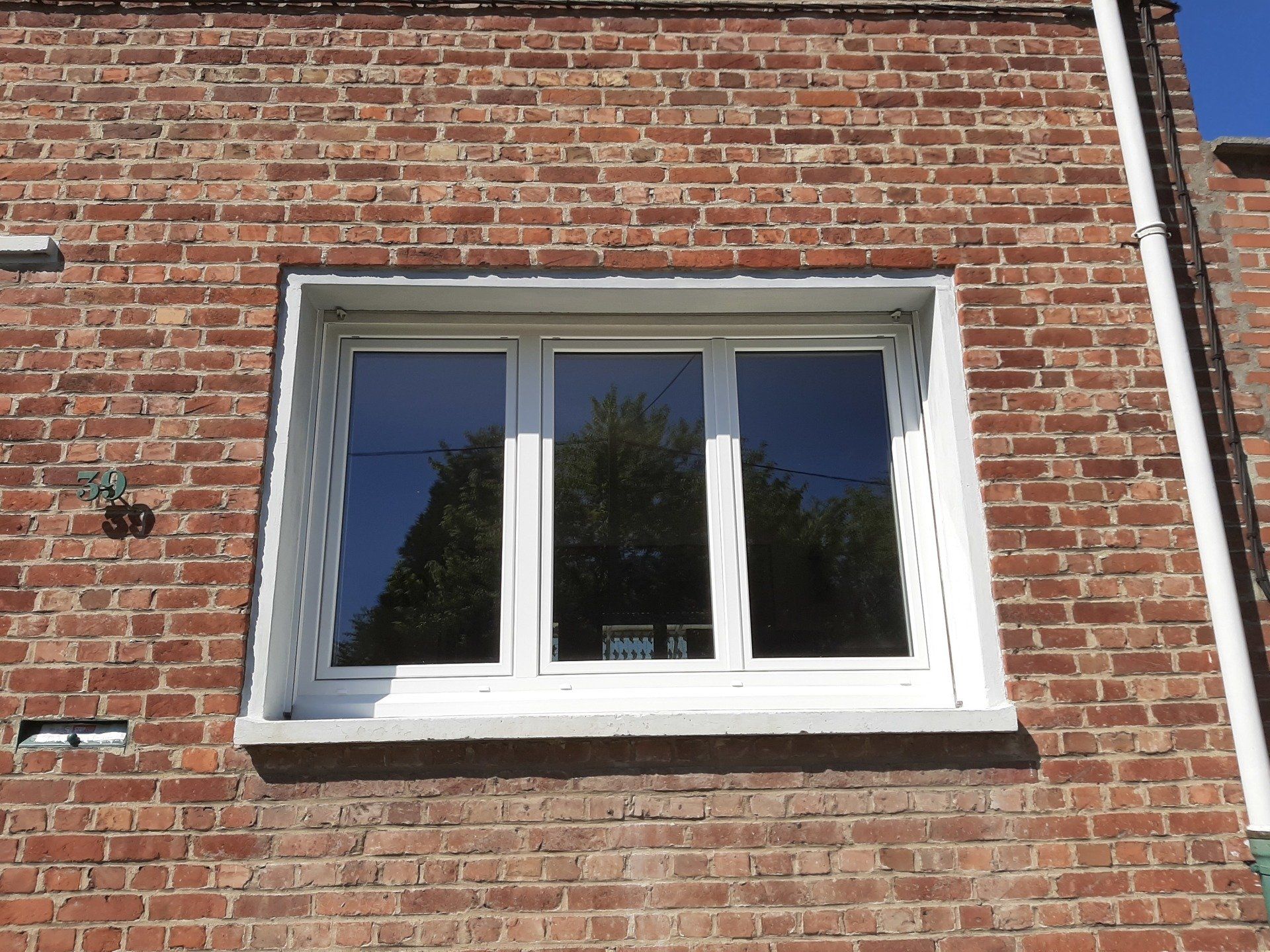 Fenêtre PVC à 3 battants sur une façade en brique