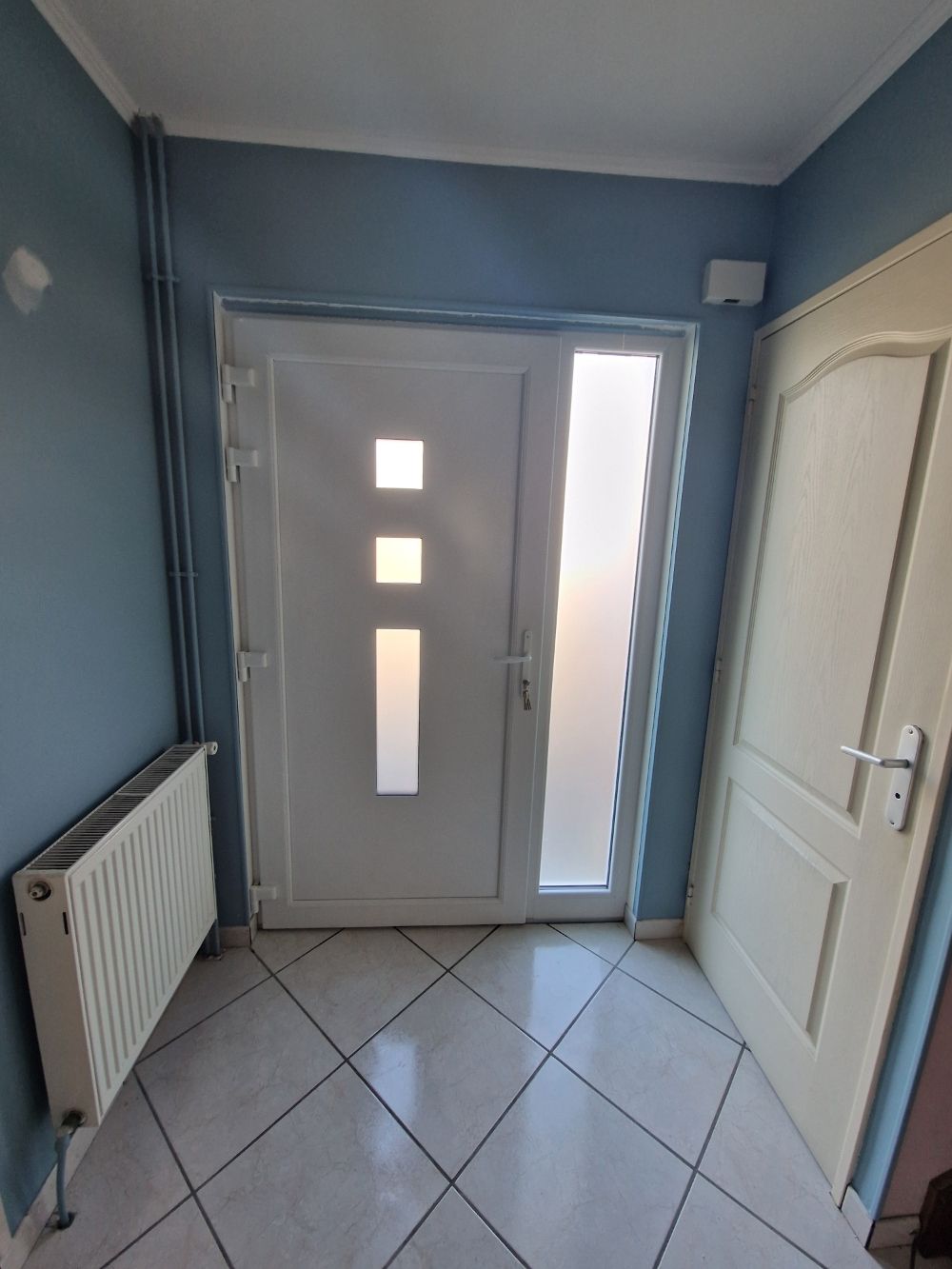 Porte d'entrée vitrée avec une grande vitre sur la droite