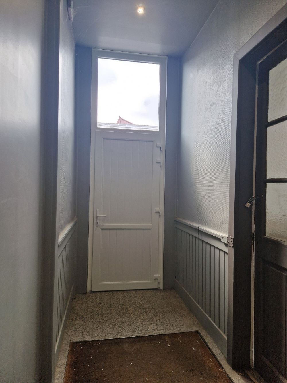 Vue intérieur d'une porte d'entrée en pvc blanc avec un vitre sur le haut