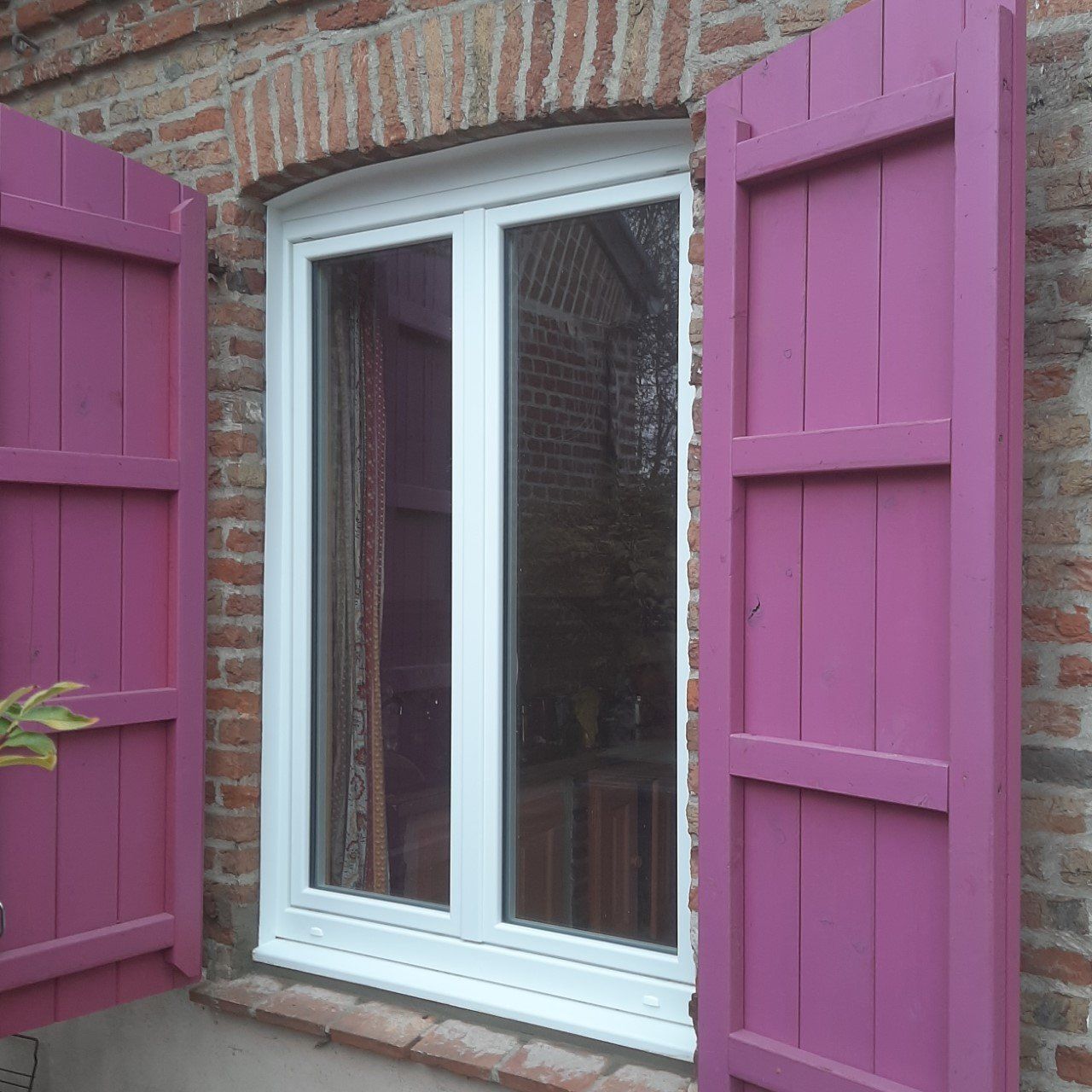 Fenêtre blanche en PVC et volets en bois peints en violet