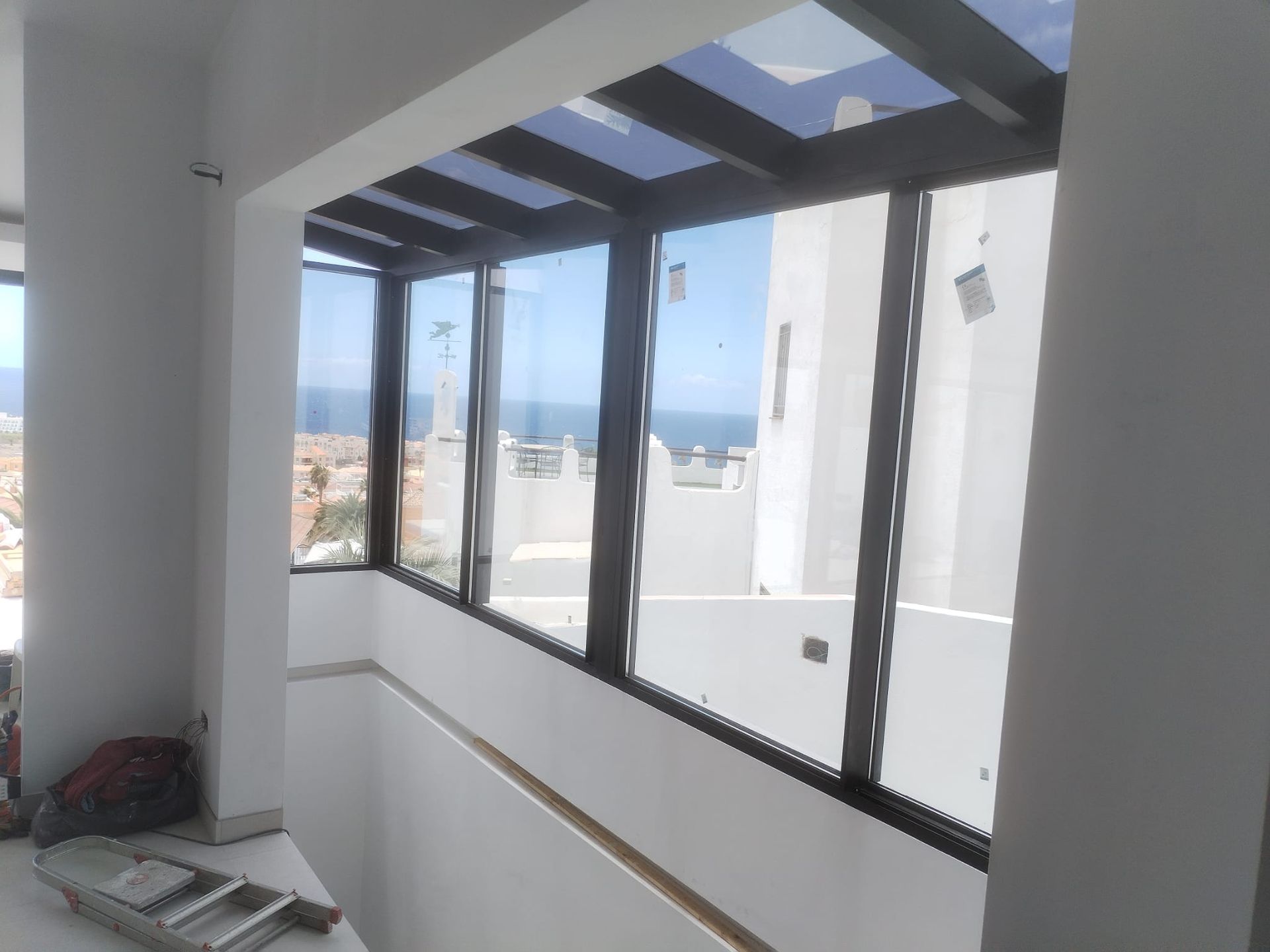 Terraza acristalada con techo y ventanas de cristal, con vista al mar.