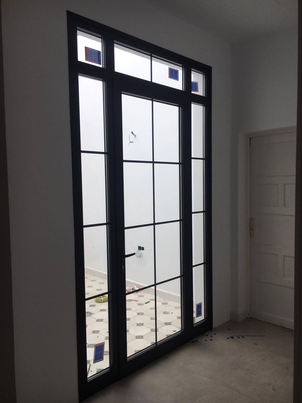 Ventana con marco negro y paneles divididos, instalada en una habitación con paredes blancas, vista oscurecida por vidrio esmerilado.