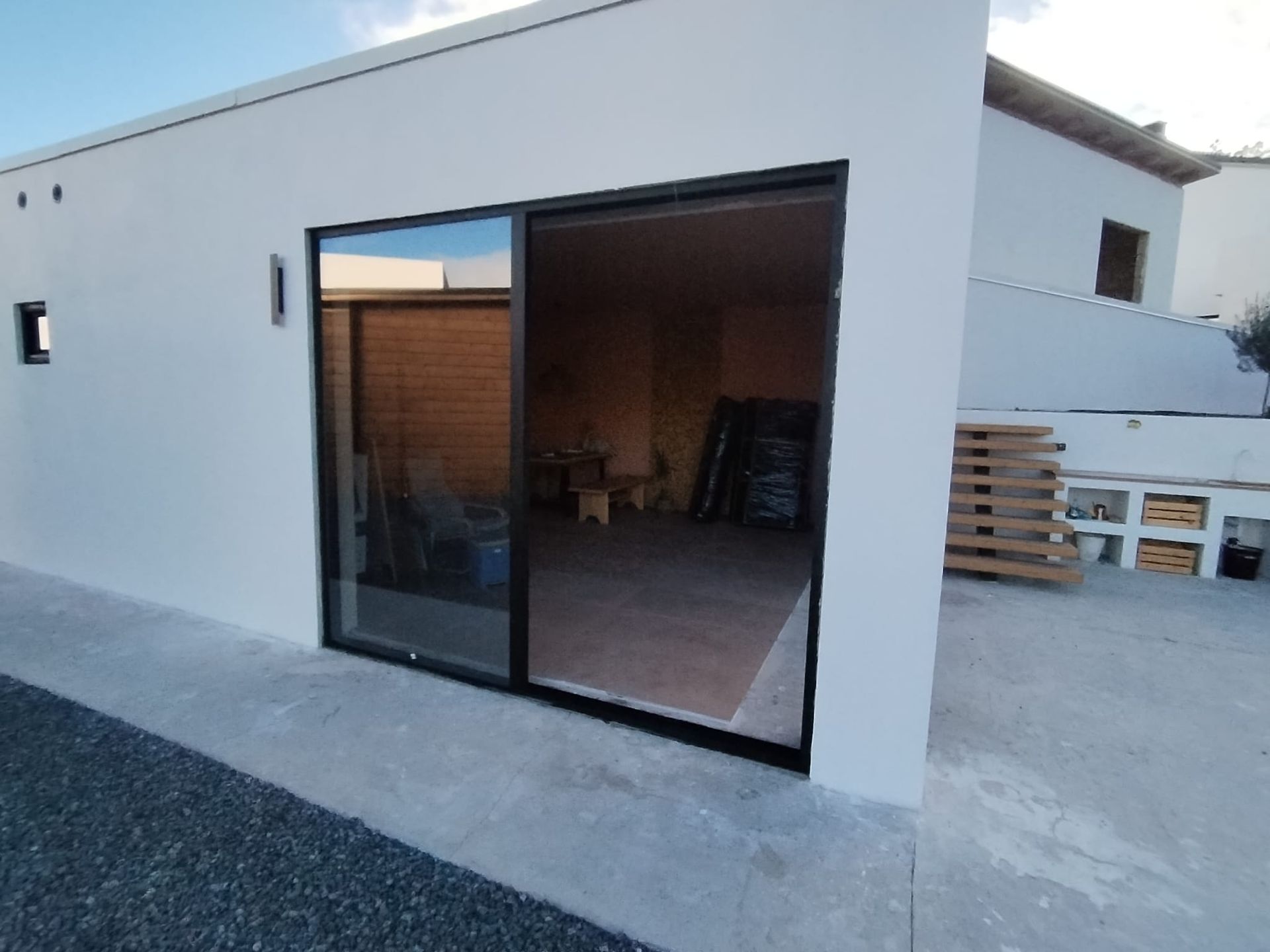 Edificio blanco con gran puerta corrediza de vidrio abierta; interior visible.