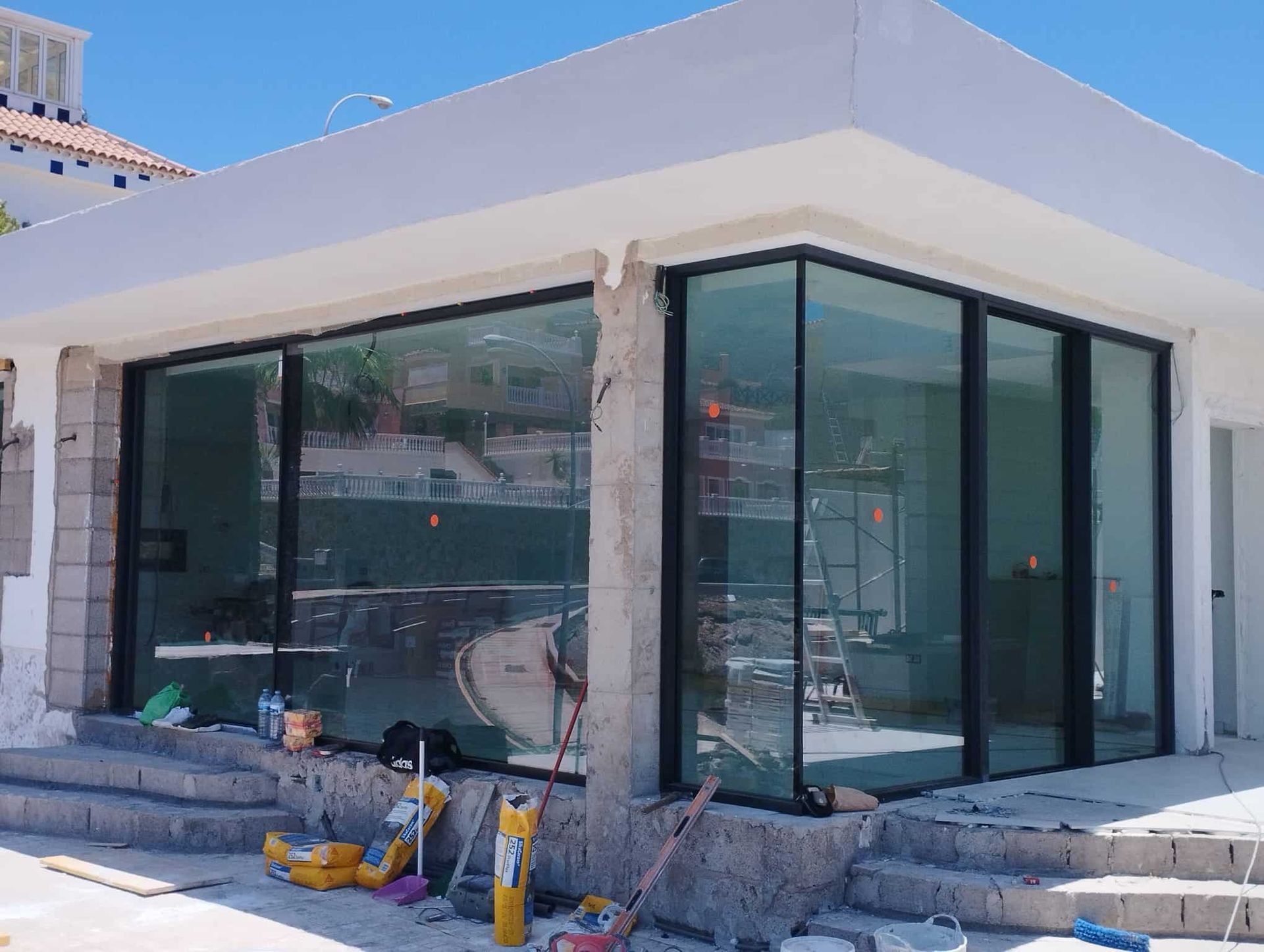 Edificio en construcción con grandes ventanales de cristal y escaleras de hormigón en el exterior.