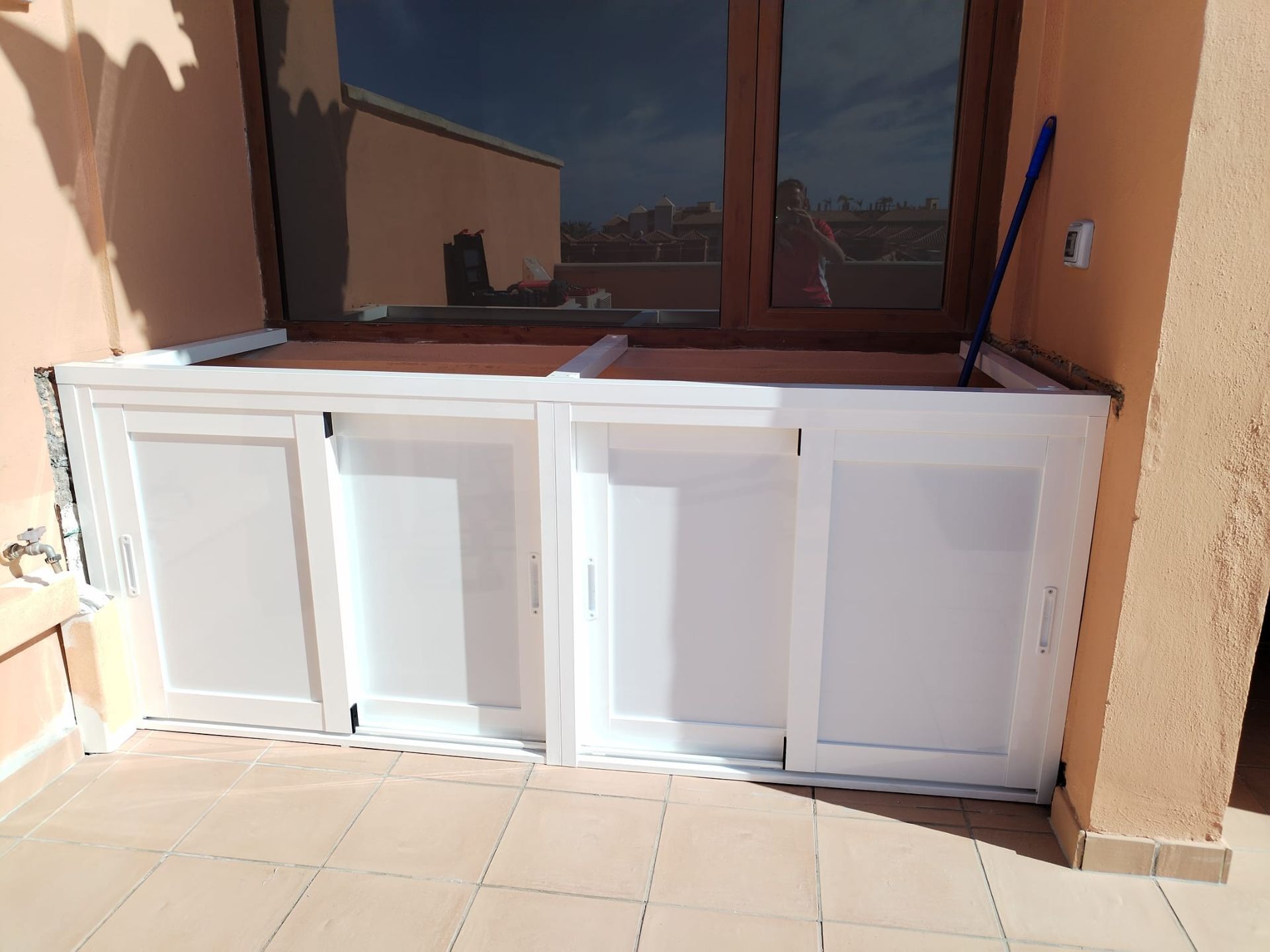 Mueble blanco debajo de una ventana en un patio.