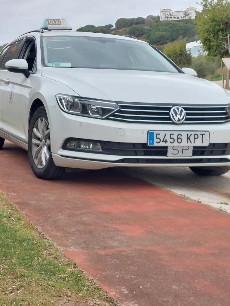 Un taxi blanco con pegatinas en la ventana, estacionado en una calle de la ciudad.