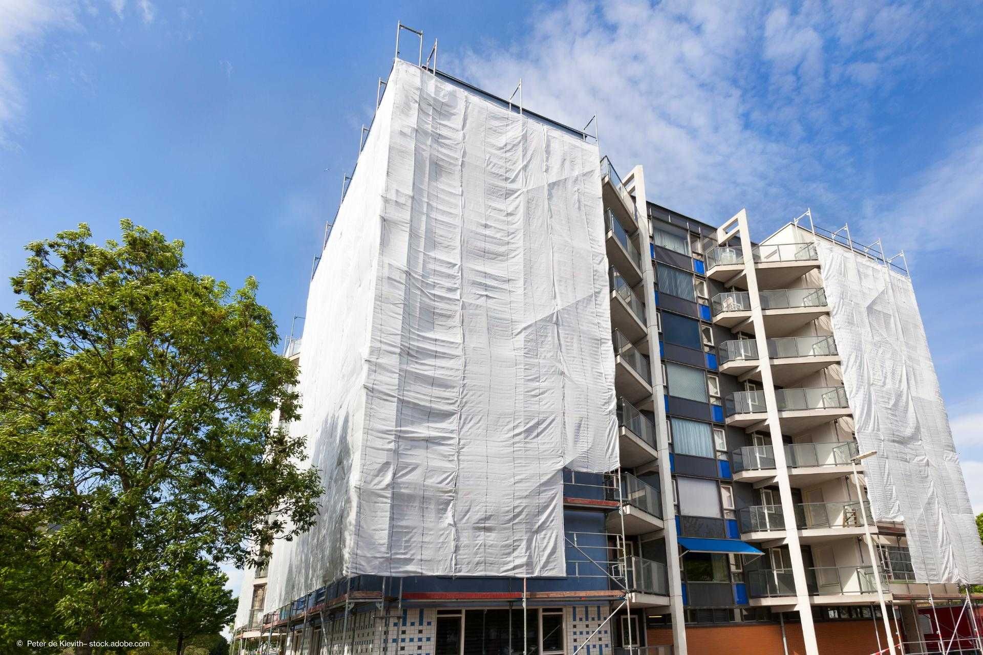 Bild von einem Gebäude, welches saniert wird mit Planen und Gerüsten.