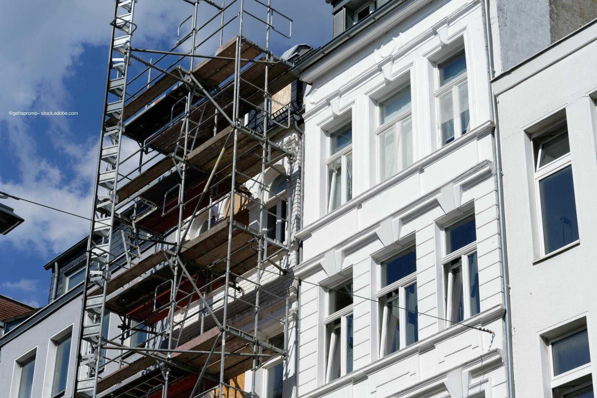 Fassadensanierung an Altbau mit Baugerüst; benachbartes Gebäude frisch gestrichen in Weiß.