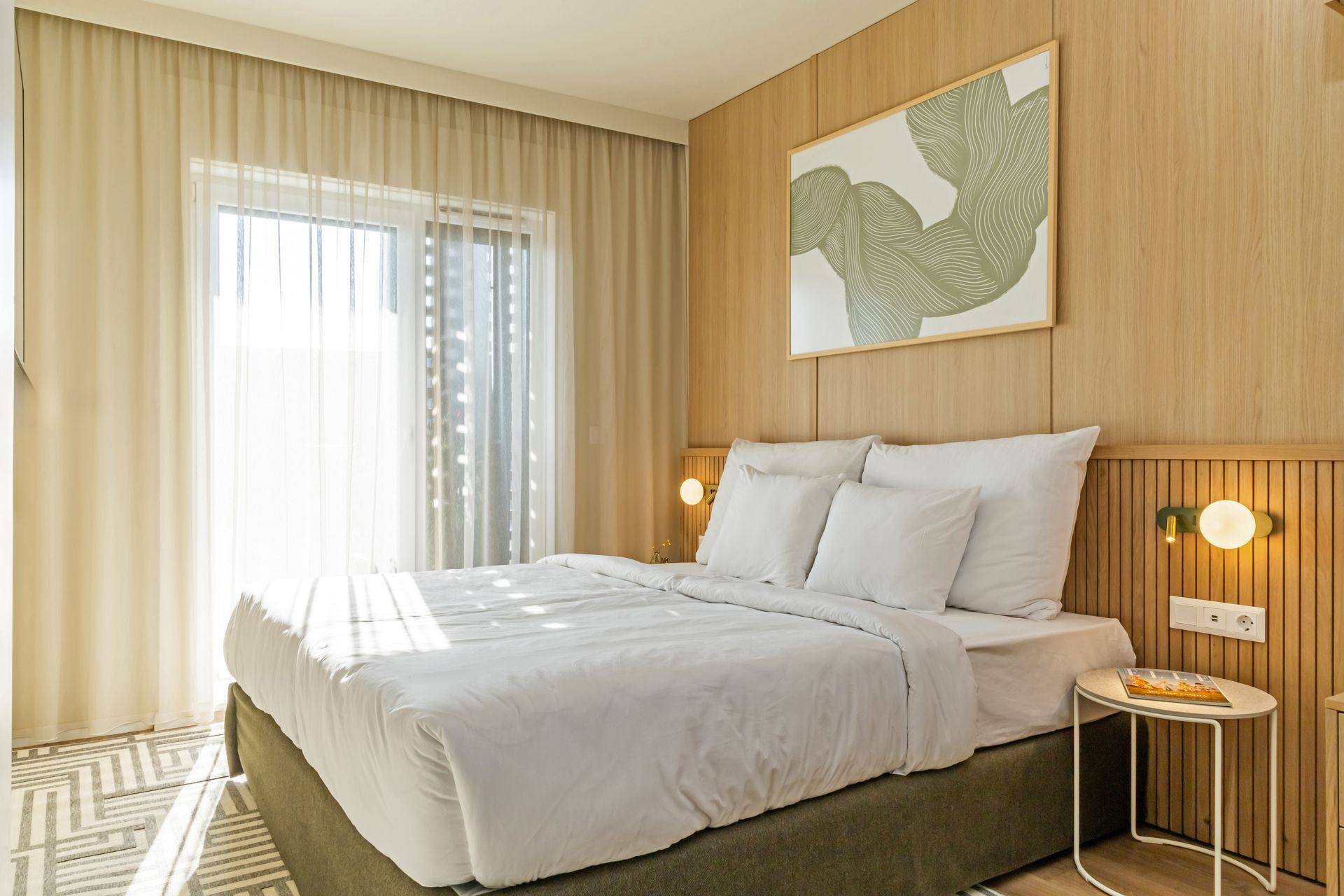 Bedroom with a bed, artwork, a door to a balcony, and wood paneling in Marone Suites Budapest.