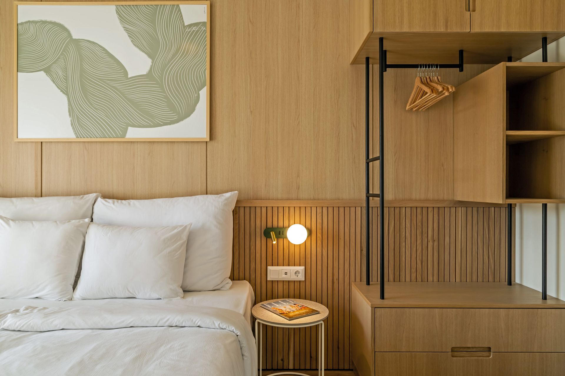 Bedroom with wooden paneling, bed with white linens, artwork, and open closet in Marone Suites Budapest.
