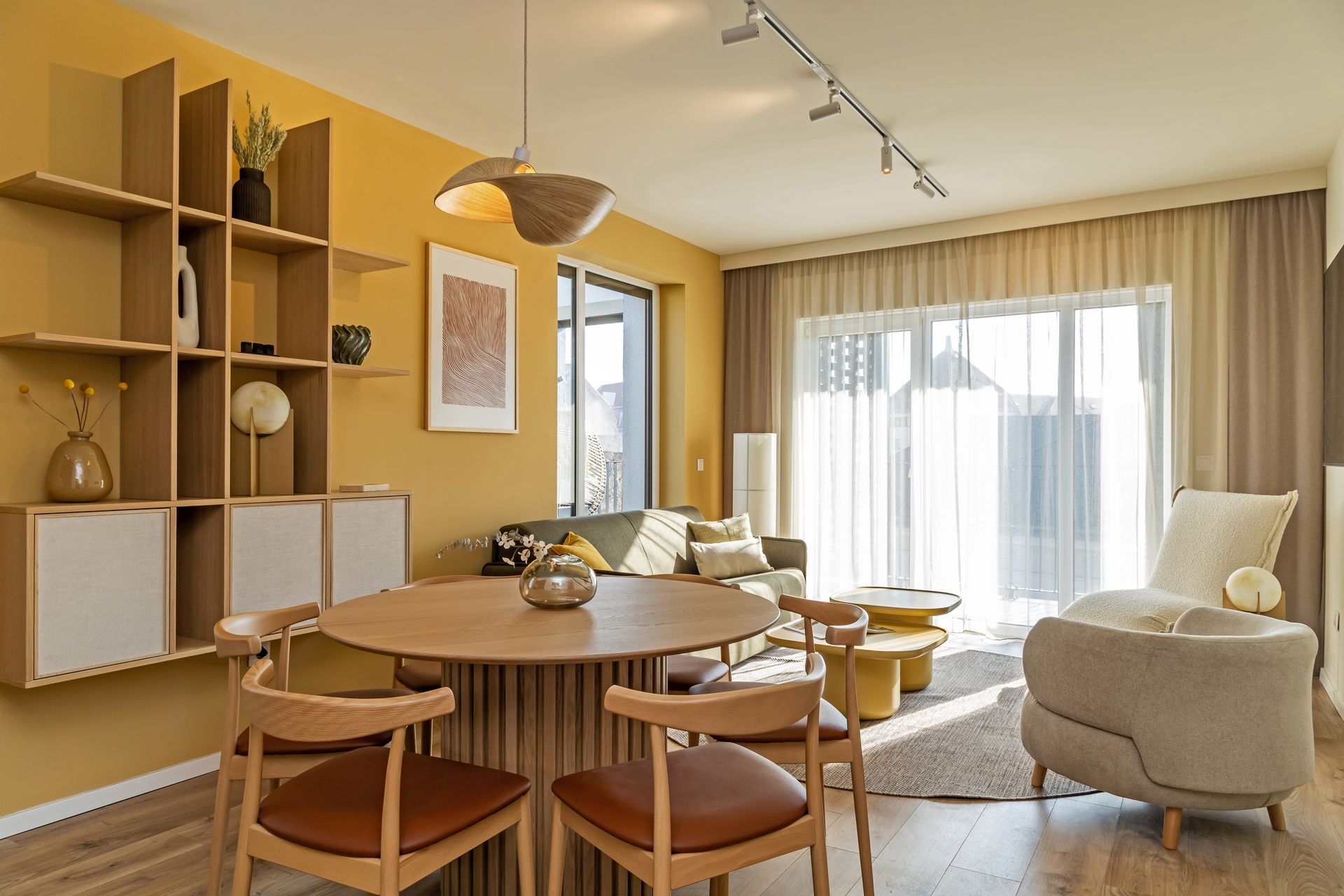 Living room with yellow and beige walls, a dining table, chairs, sofa, and a built-in shelf unit in Marone Suites Budapest.