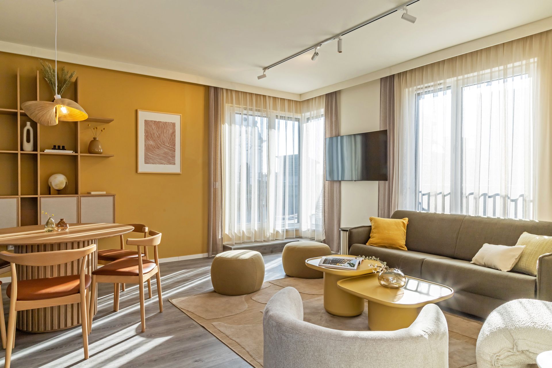 Living room with sofa, round coffee tables, dining area and lots of light. Glass door leading to a rooftop in Marone Suites.