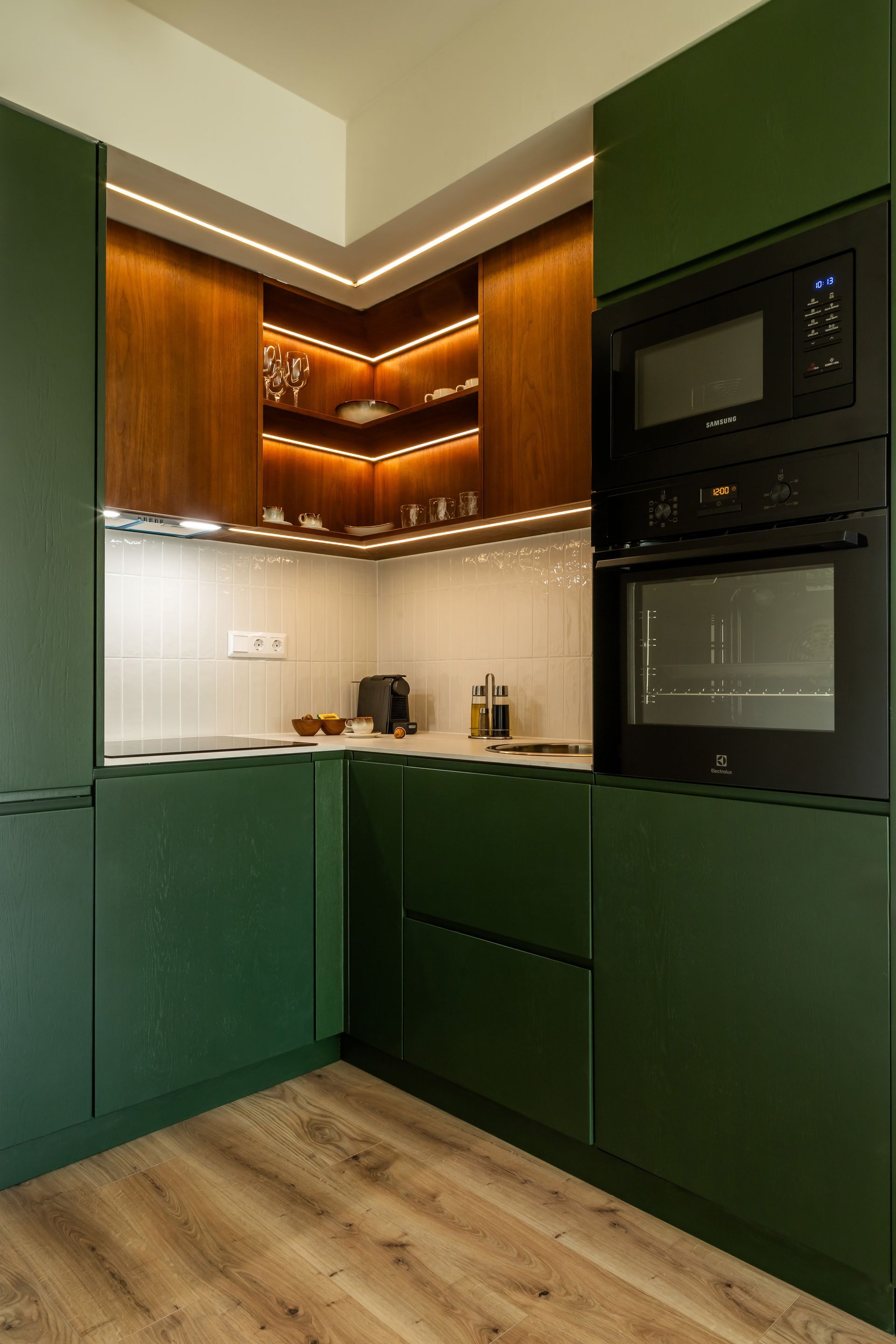 Green modern kitchen with wood cabinets, built-in appliances, and recessed lighting in Marone Suites Budapest.