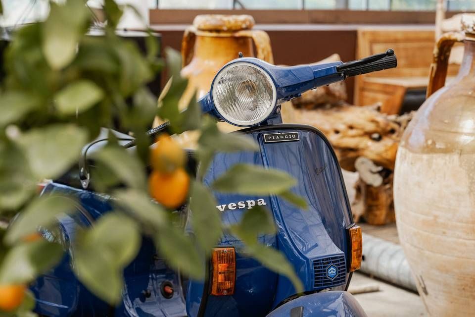 Ein blauer Vespa-Roller hinter einem Orangenbaum