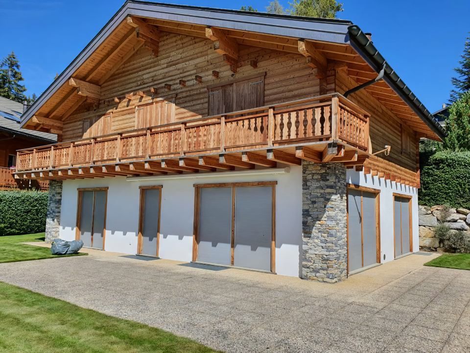 Une grande maison en bois avec un balcon et deux garages