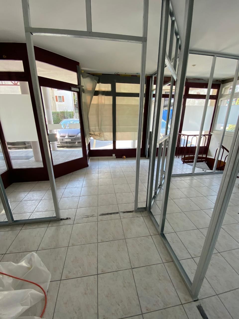 Une pièce avec beaucoup de fenêtres et un sol en carrelage blanc.