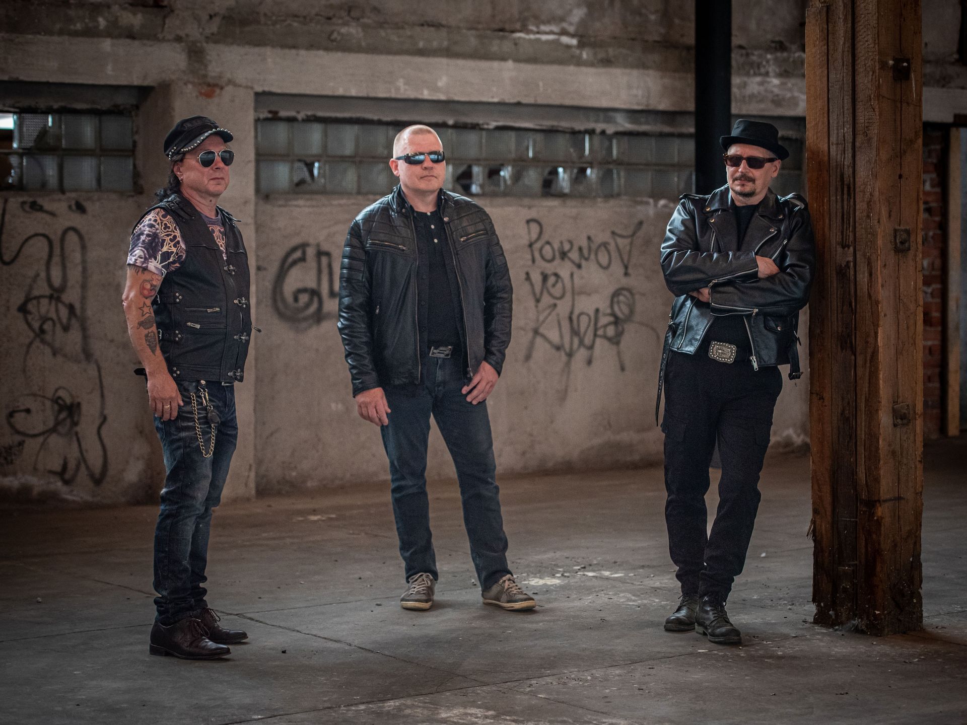 Kolme miestä seisoo vierekkäin tyhjässä huoneessa.