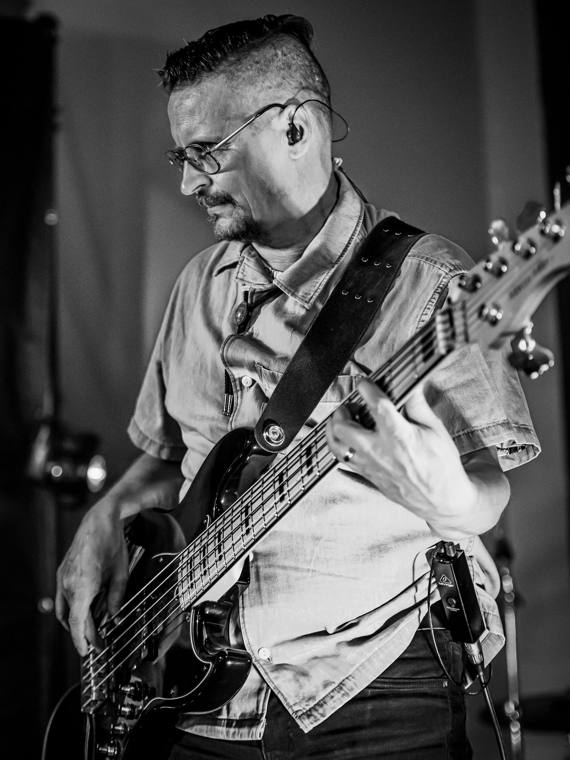 Mies soittaa bassokitaraa mustavalkoisessa valokuvassa.