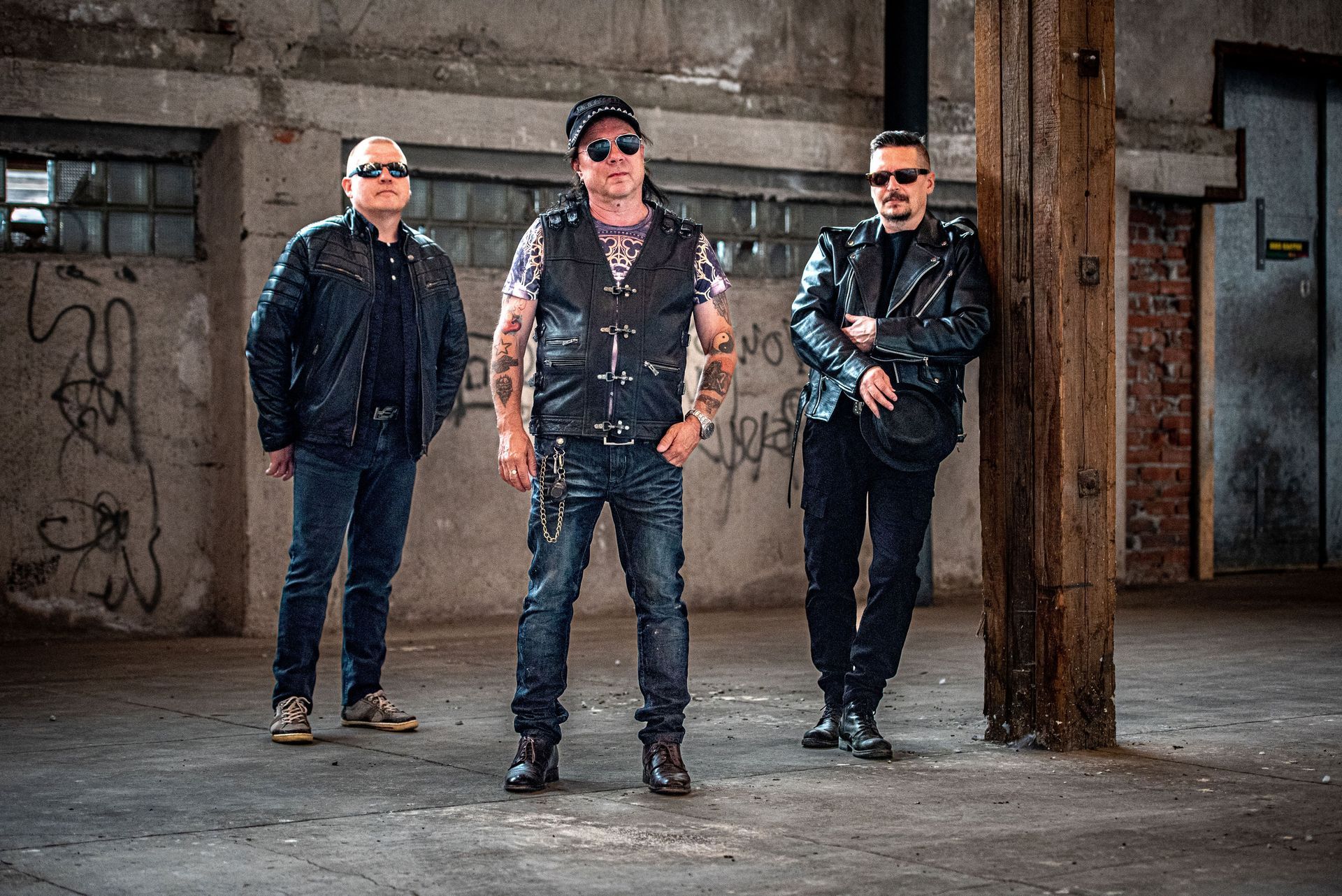 Kolme miestä seisoo vierekkäin tyhjässä rakennuksessa.