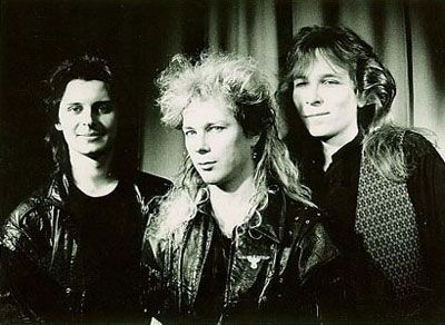 Kolme miestä poseeraa mustavalkoista kuvaa varten.