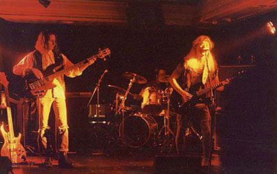 Ryhmä ihmisiä soittamassa instrumentteja lavalla pimeässä huoneessa