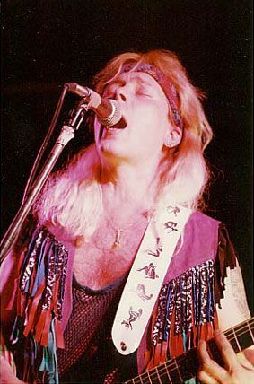 Nainen laulaa mikrofoniin soittaessaan kitaraa