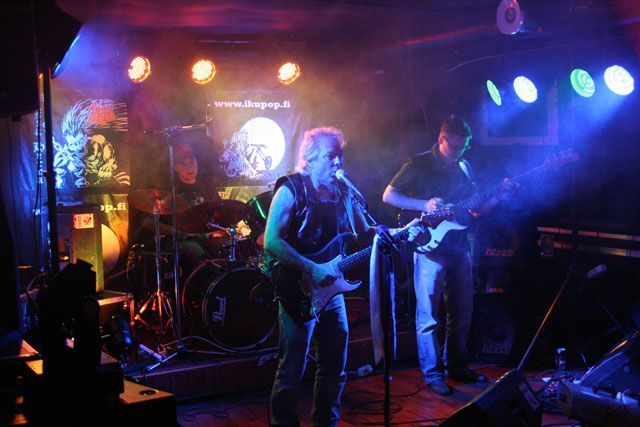 Mies soittaa kitaraa ja laulaa mikrofoniin lavalla.