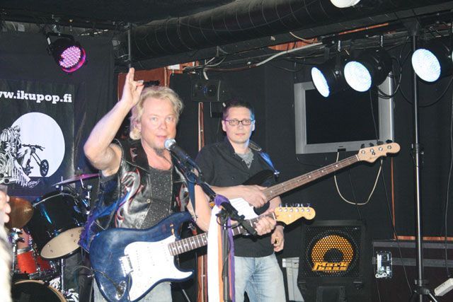 Mies laulaa mikrofoniin samalla kun toinen mies soittaa kitaraa