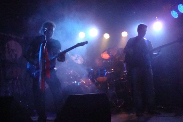 Mies laulaa mikrofoniin soittaessaan kitaraa