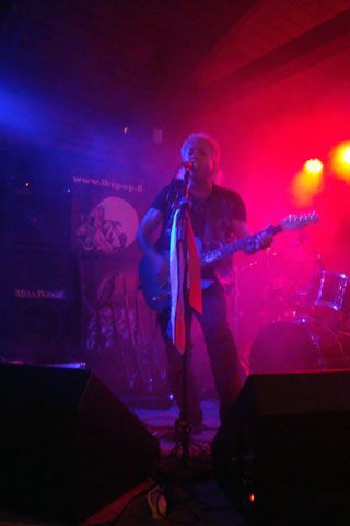 Mies laulaa mikrofoniin soittaessaan kitaraa