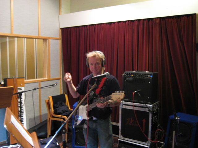 Mies soittaa kitaraa mikrofonin edessä