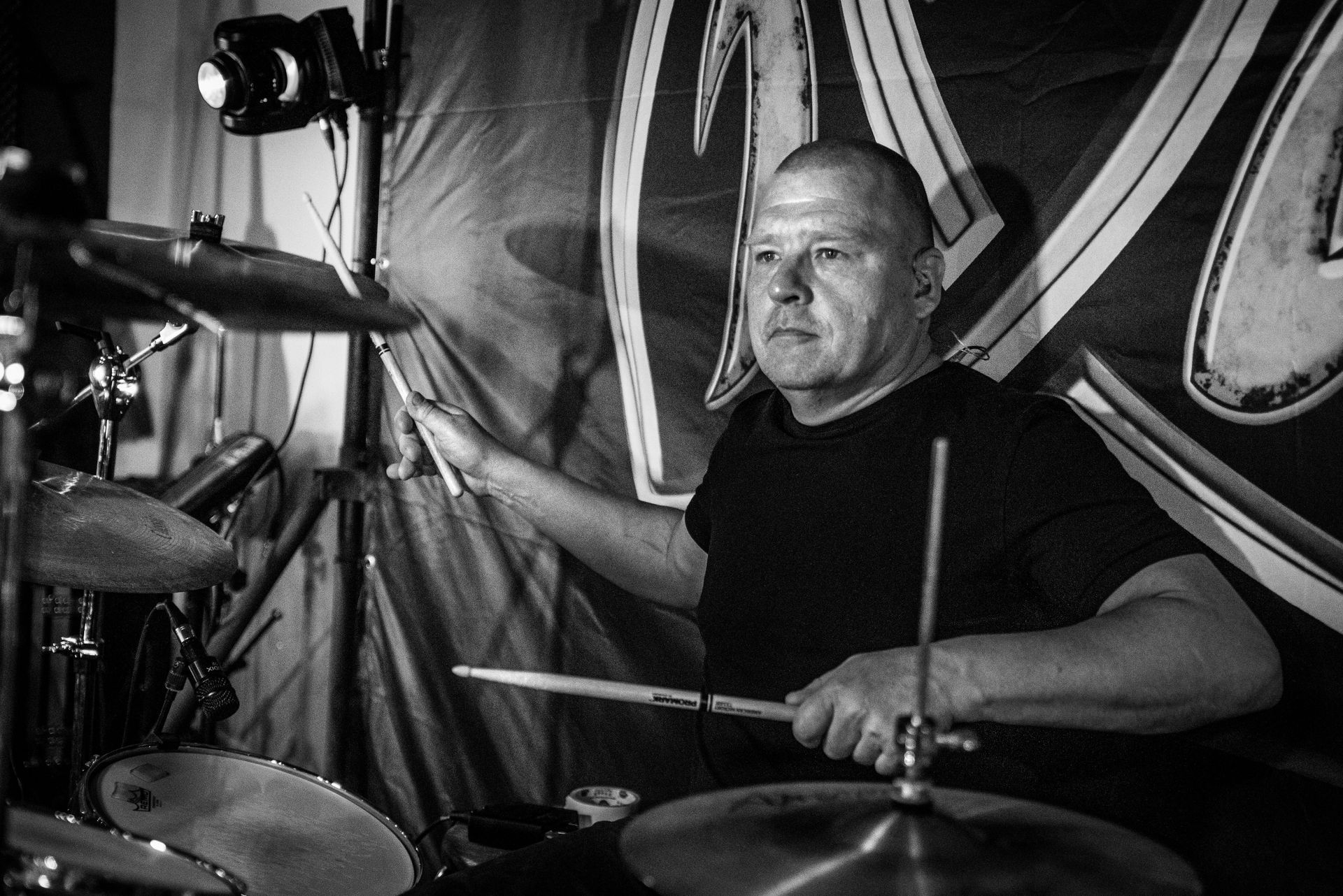 Mies soittaa rumpuja mustavalkoisessa valokuvassa.