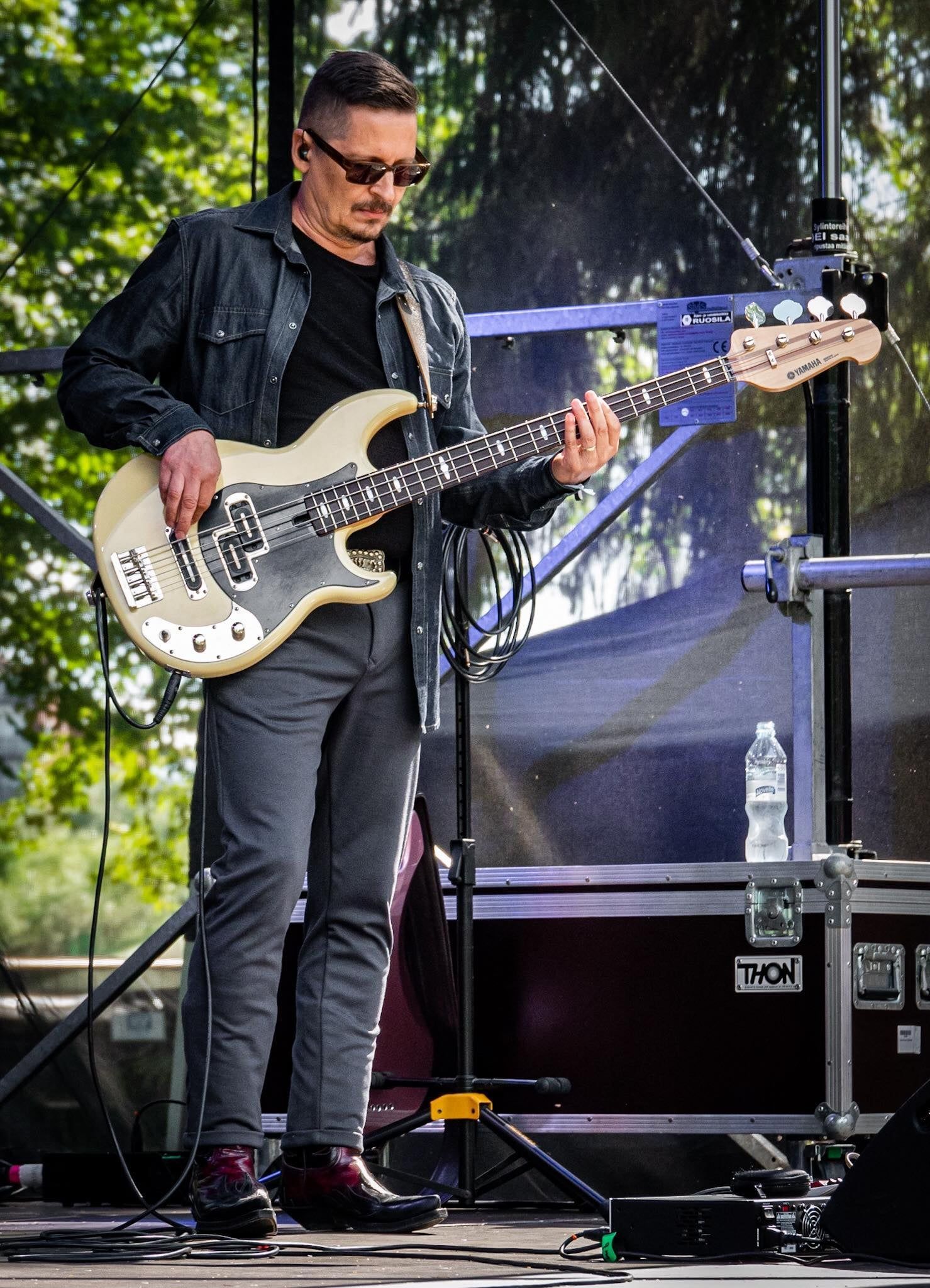 Mies soittaa bassokitaraa lavalla.