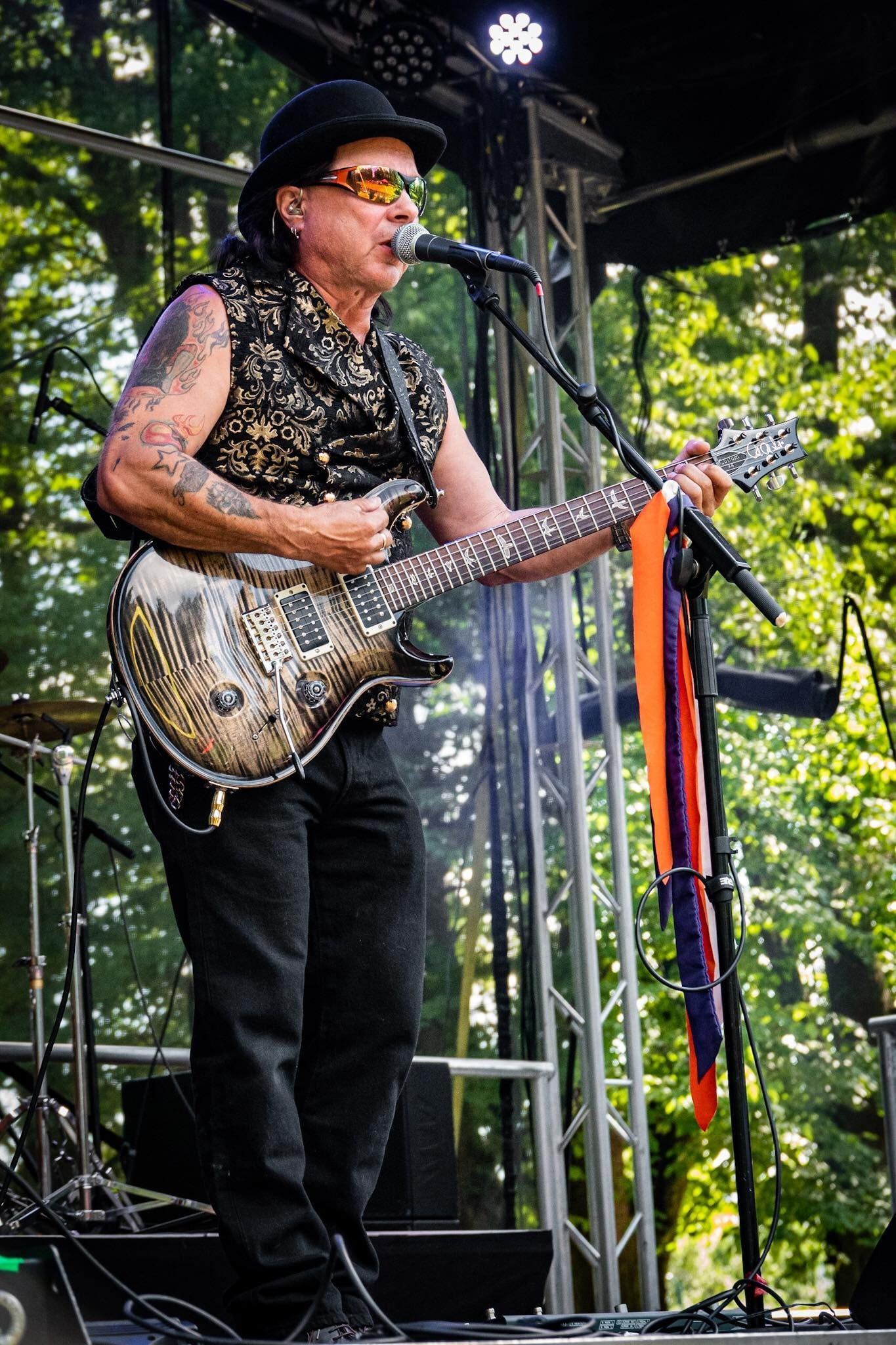 Mies soittaa kitaraa ja laulaa mikrofoniin lavalla.