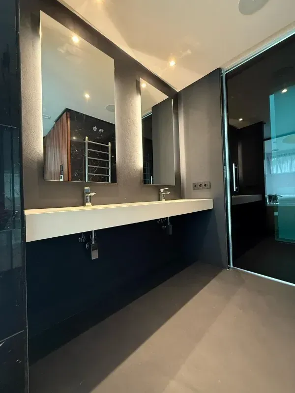 Baño moderno con dos espejos, lavabos y una combinación de colores gris oscuro.