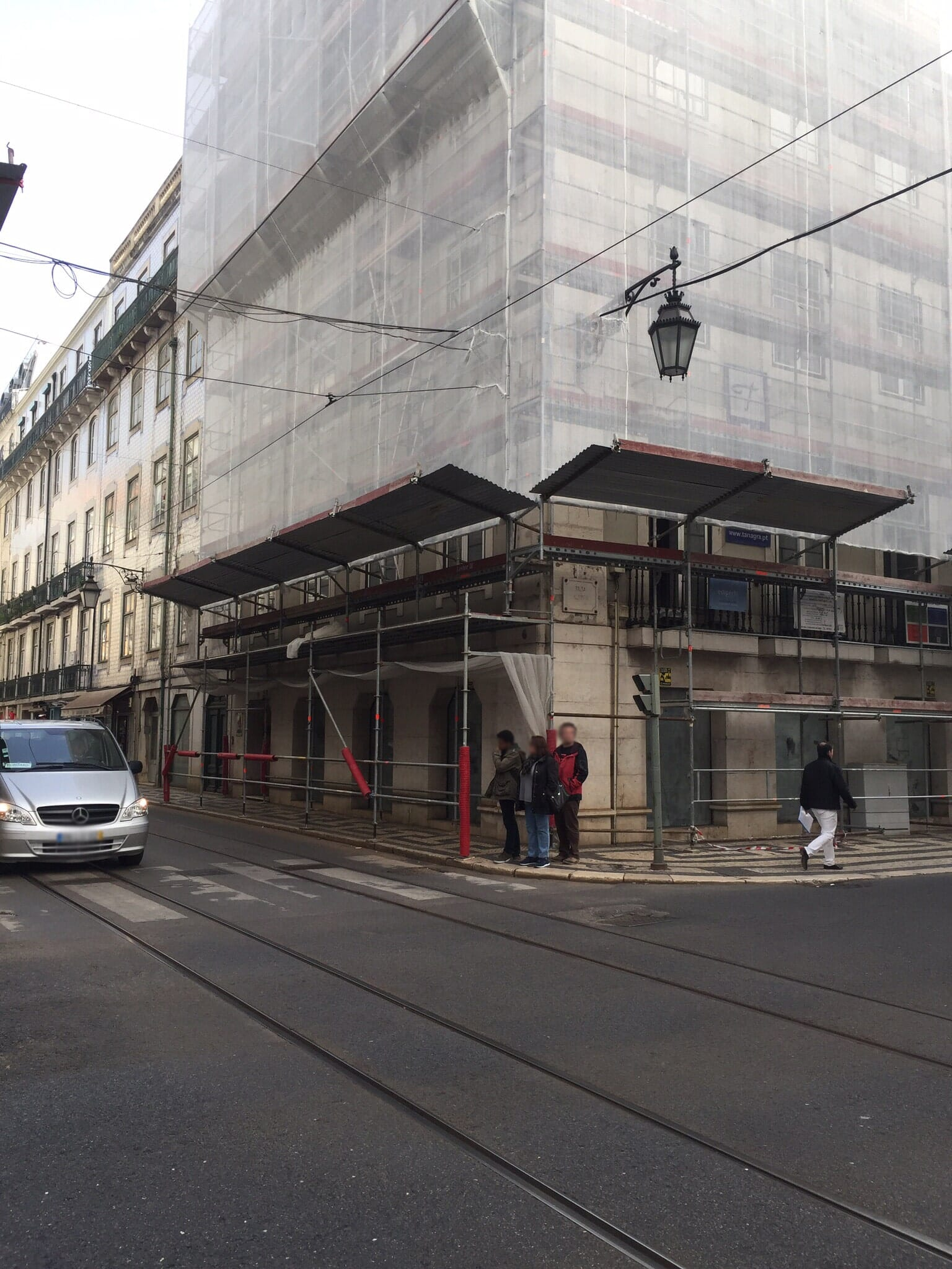 Um carro está estacionado na beira da estrada em frente a um prédio em construção.