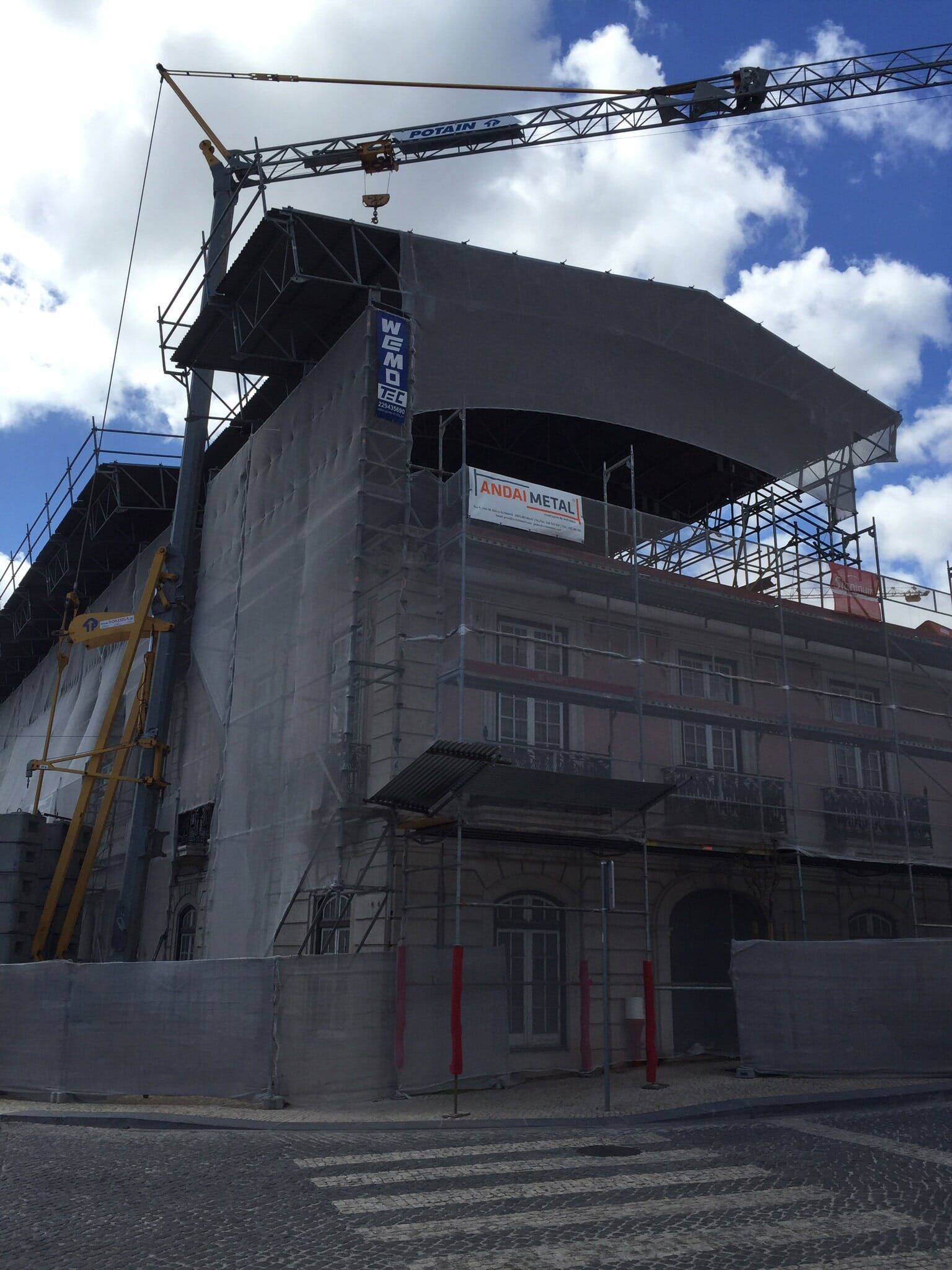 Um grande edifício está sendo construído com andaimes e um guindaste.