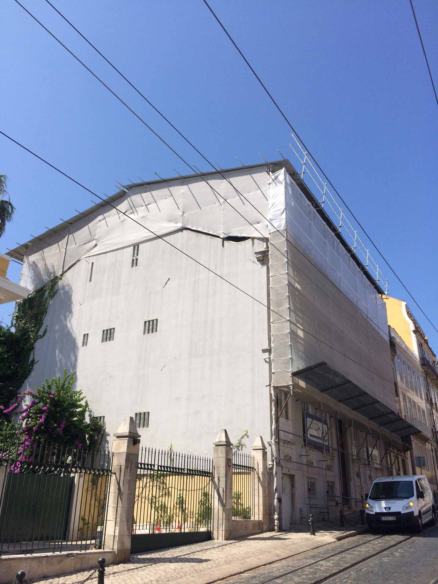 Uma van branca está estacionada em frente a um grande prédio branco.