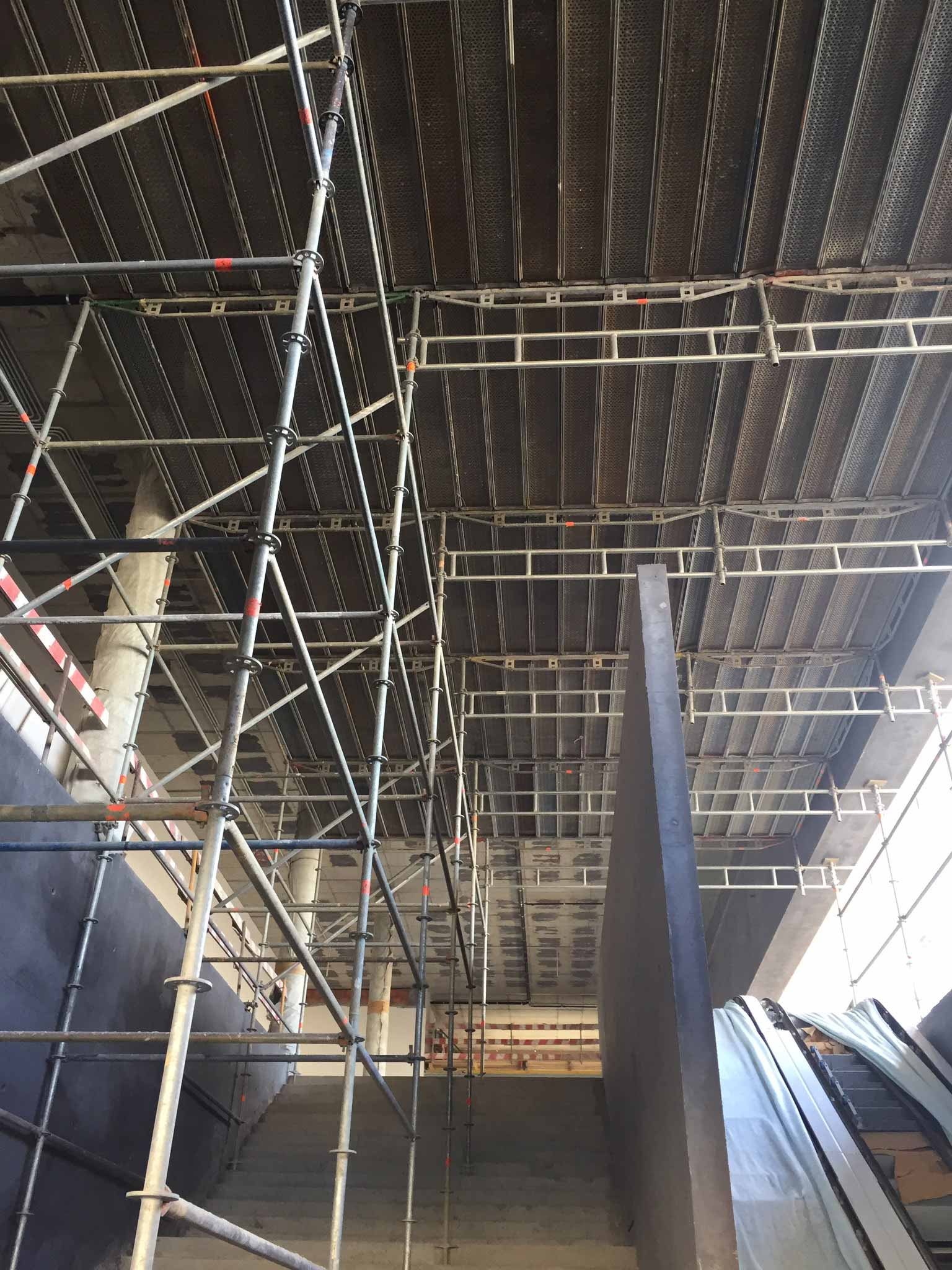 Um edifício em construção com andaimes e escadas rolantes.
