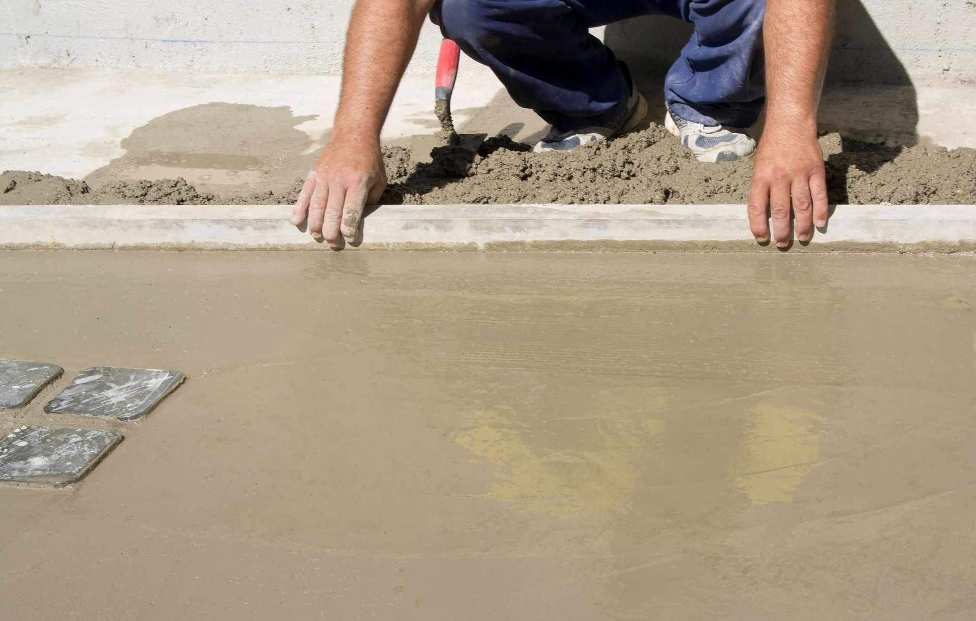 Ouvrier lissant du béton frais à la main sur un chantier de construction