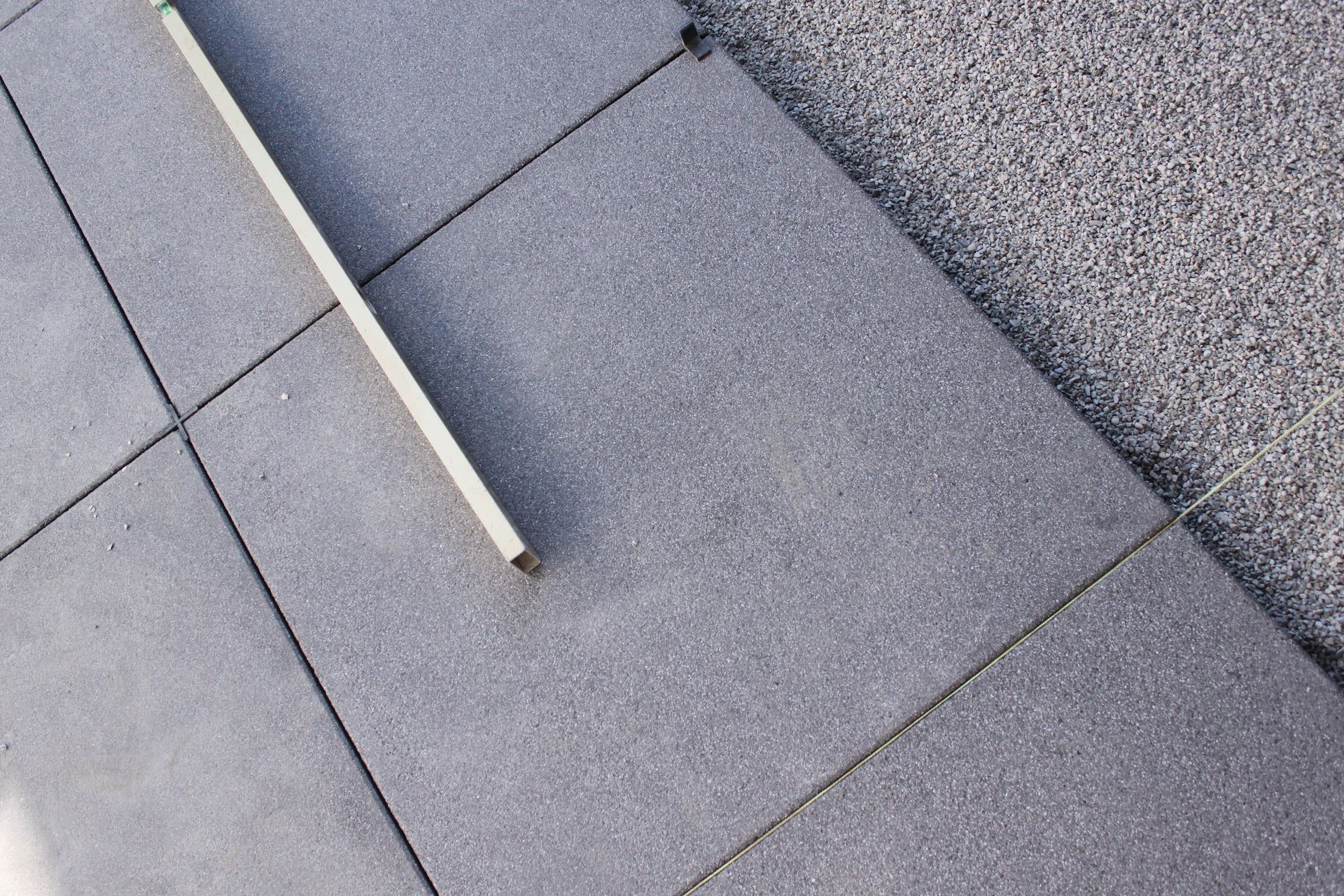 Tige blanche sur un dallage carrelé gris, près d'un bord de trottoir moucheté