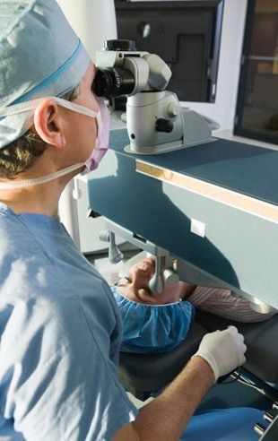 Un cirujano está mirando a través de un microscopio en un quirófano.